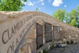 Rock and masonry sculpture shaped like a curved wall, displaying carved decorative text and informational panels.