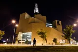  A silhouette of a person faces the exterior north side of the Museum at night (the limestone mountain).