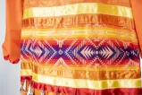This section of the orange jingle dress made up of multiple colourful ribbons. 