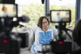 Woman sitting on a couch in front of two video cameras.