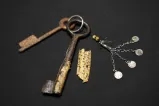 Two large skeleton keys with small handwritten note and keychain.