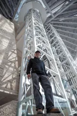 Antoine Predock, the architect of the Museum, is pictured inside the Museum from a low angle with white beams rising above him.