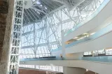 The interior of a large open spaced part of the Museum. We see the glass panels, and a three level white terrace