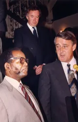 Two men talking. Both are wearing suits.