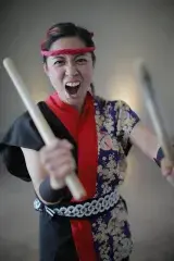 A female drummer holds up her sticks.