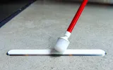 The end of a cane touches a raised strip attached to the floor.