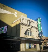 A photo of an old theatre. A sign on the side of the building says “Burton Cummings Theatre.”