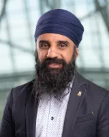 A man of Indian background, smiling and wearing a dark blue dastar and grey blazer.