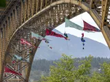 Several large triangular banners hang from the bottom of a large bridge.
