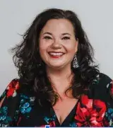 Woman with dark shoulder length hair and a floral top.