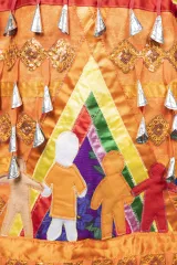 This section of the orange jingle dress shows two human figures inside a multicoloured tipi. One of the figures is wearing an orange shirt.