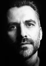 Man with a moustache and short beard. Photographed in black and white.