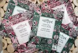 Packages with colourful Haida-themed designs sit in a pile. The large text on the packages reads “Candied Wild Sockeye Salmon” or “Candied Wild Pink Salmon”. Smaller text reads “Oncorhynchus nerka” , “60g”, “ready to eat”, “sustainable”, and “Authentic Indigenous Seafood”