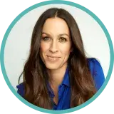 A middle-aged woman with long dark hair wears a blue blouse.