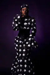 A drag queen dressed from head to toe in a long, black mermaid style dress decorated with a white printed design.