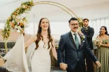 A man in a suit and a woman in a wedding dress holding hands.
