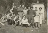 A group of men pose for a picture with trees in the background.