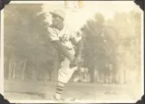 A young man in baseball uniform throwing a pitch.