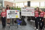Two posters displayed on easels with a total of groups of two students standing on either side of them. 