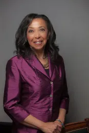 A Black woman smiles at the camera.