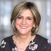 A woman in a flowered top looks at the camera.