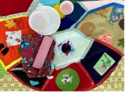 Overhead view of colourful, handmade quilted fabric, created by past attendees of the Full Moon teachings. When it is fully opened, the quilt features floral and geometric designs in red, blue, green and gold tones that form into a turtle with representations of the full moons.