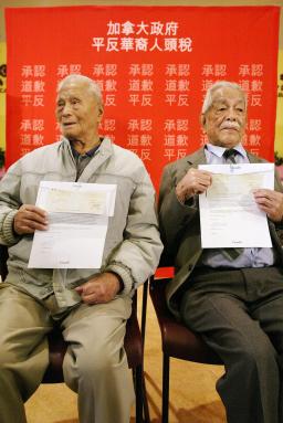 Two old men sit holding papers in front of them.Immigration.
