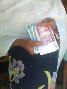 A Rohingya woman’s hands are holding Myanmar currency called “kyat” (pronounced “chat”).