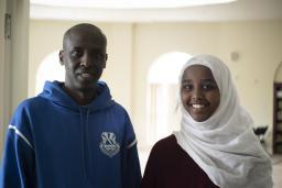 A man stands next to a young woman wearing a headscarf. 