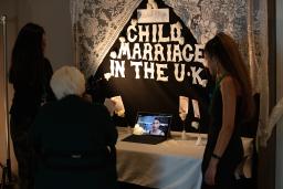 Two students talking about their project, “Child Marriage in the UK,” with a member of the public.