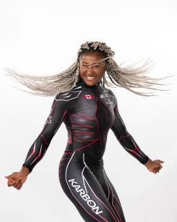 A black woman with a bobsleigh olympic uniform poses with her hair flowing.