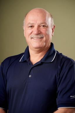 Devin Beaudry, a smiling, middle-aged man wearing a dark blue polo shirt with white piping along the collar