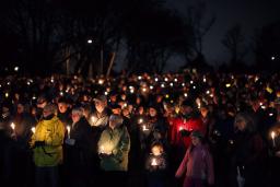A large crowd of people gathered outside at night, holding candles.