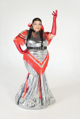 A drag queen is dressed in a silver and red gown with matching red gloves.
