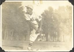 A young man in baseball uniform throwing a pitch.