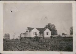Black-and-white image of a farmhouse in a field