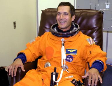 A smiling man in an orange astronaut jumpsuit.