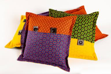 A pile of cushions covered with brightly coloured material.
