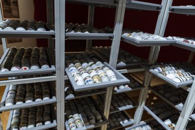 Thousands of small, porcelain cups are arranged in trays in a high metal rack.