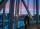 Two individuals stand looking through the floor-to-ceiling glass windows at the Winnipeg skyline. The sun is setting.