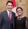 Prime Minister Justin Trudeau, left, and Nimrat Randhawa, right, pose for a photograph in front of a Canadian flag. They are both smiling at the photographer.