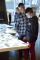 An adult man and a teenaged boy stand beside one another looking down at an interactive table.