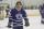 Un jeune homme portant un uniforme de hockey bleu orné d'un logo de couronne sur une patinoire intérieure.