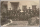 A nun and a group of First Nations children in school uniforms posing in front of a stone building.