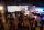 A crowd of people watches a band play on a brightly lit stage.