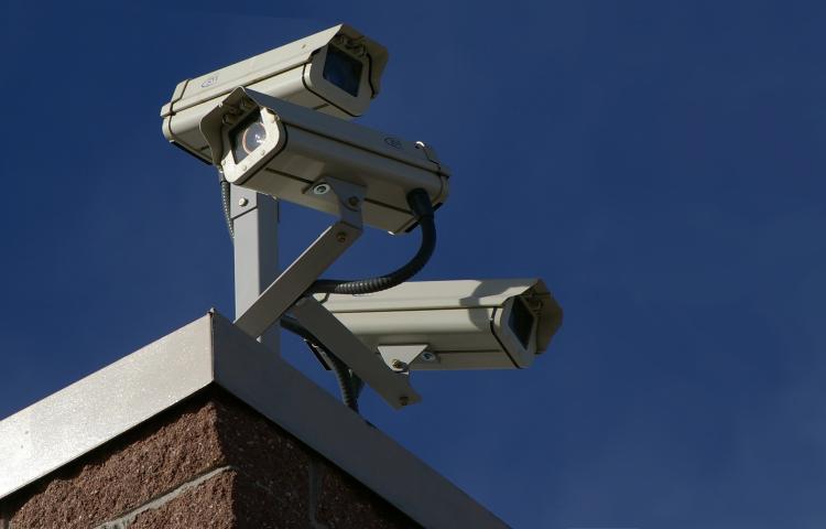 Three surveillance cameras on the corner of a building Partially obscured.