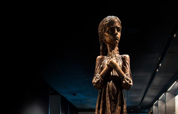 A statue of a girl holding stalks of wheat. Partially obscured.