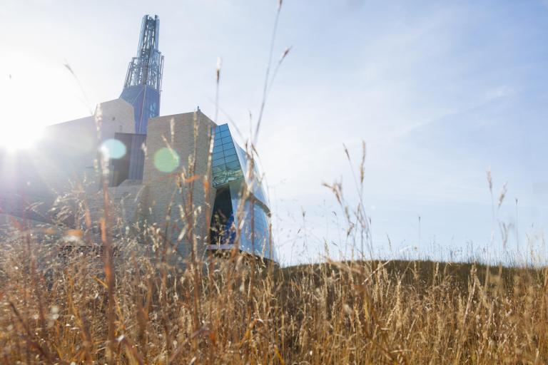 Exterior view of the museum architecture with prairie grass in the foreground Partially obscured.