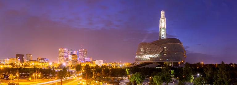 A panoramic shot of the Museum and the Winnipeg skyline at dusk. Partially obscured.