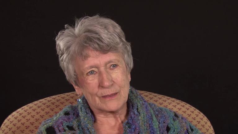 A head-and-shoulders image of Huberte Gautreau. She is sitting in a chair, wearing a shawl and looking at someone who is out of the frame. Partially obscured.